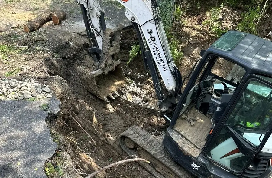 Excavator digging alongside a gravel drive