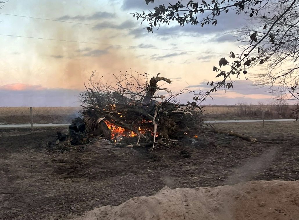 Brush pile burning at dusk on a cleared field