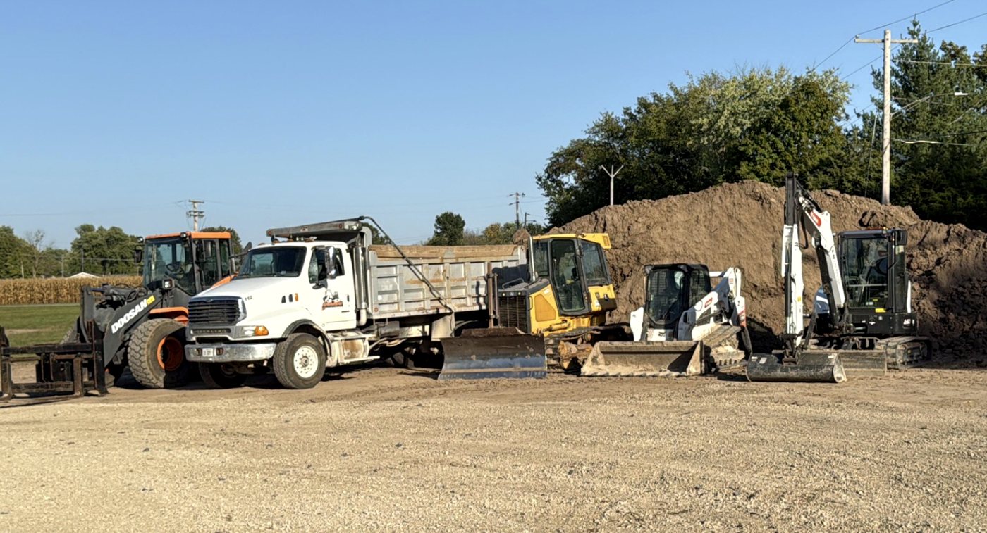 Dump truck and skid steer working dirt stockpiles
